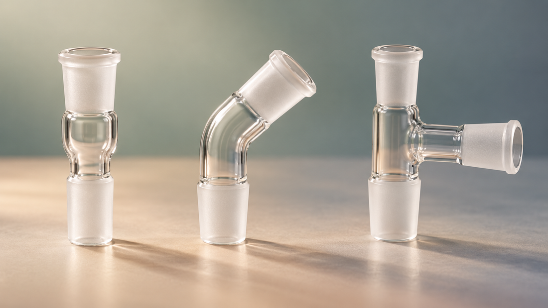 Three clear glass joint adapters on a soft sage, sand and slate background
